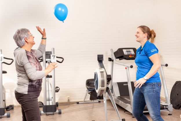 neurologische aandoening mevrouw houdt een ballon omhoog met behulp van de fysiotherapeut