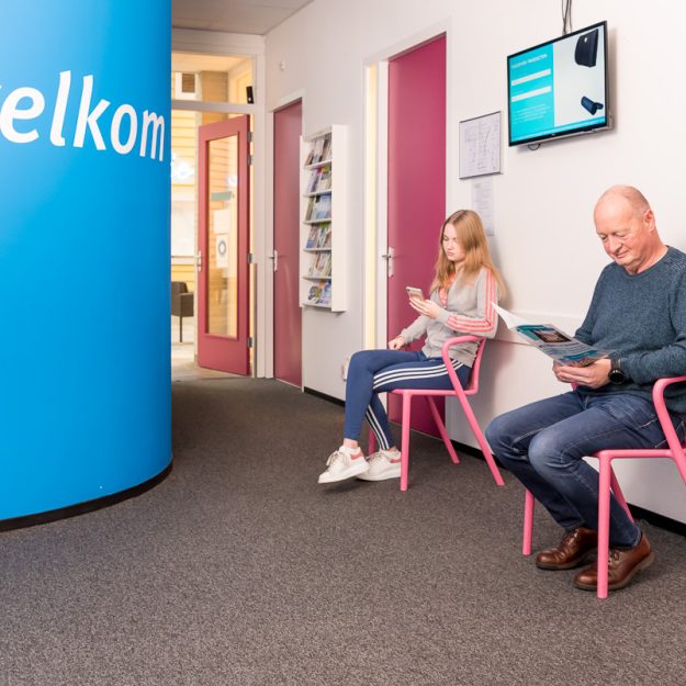 Twee mensen die wachten op hun beurt, maar polsklachten krijgen door smartphone gebruik ondertussen.