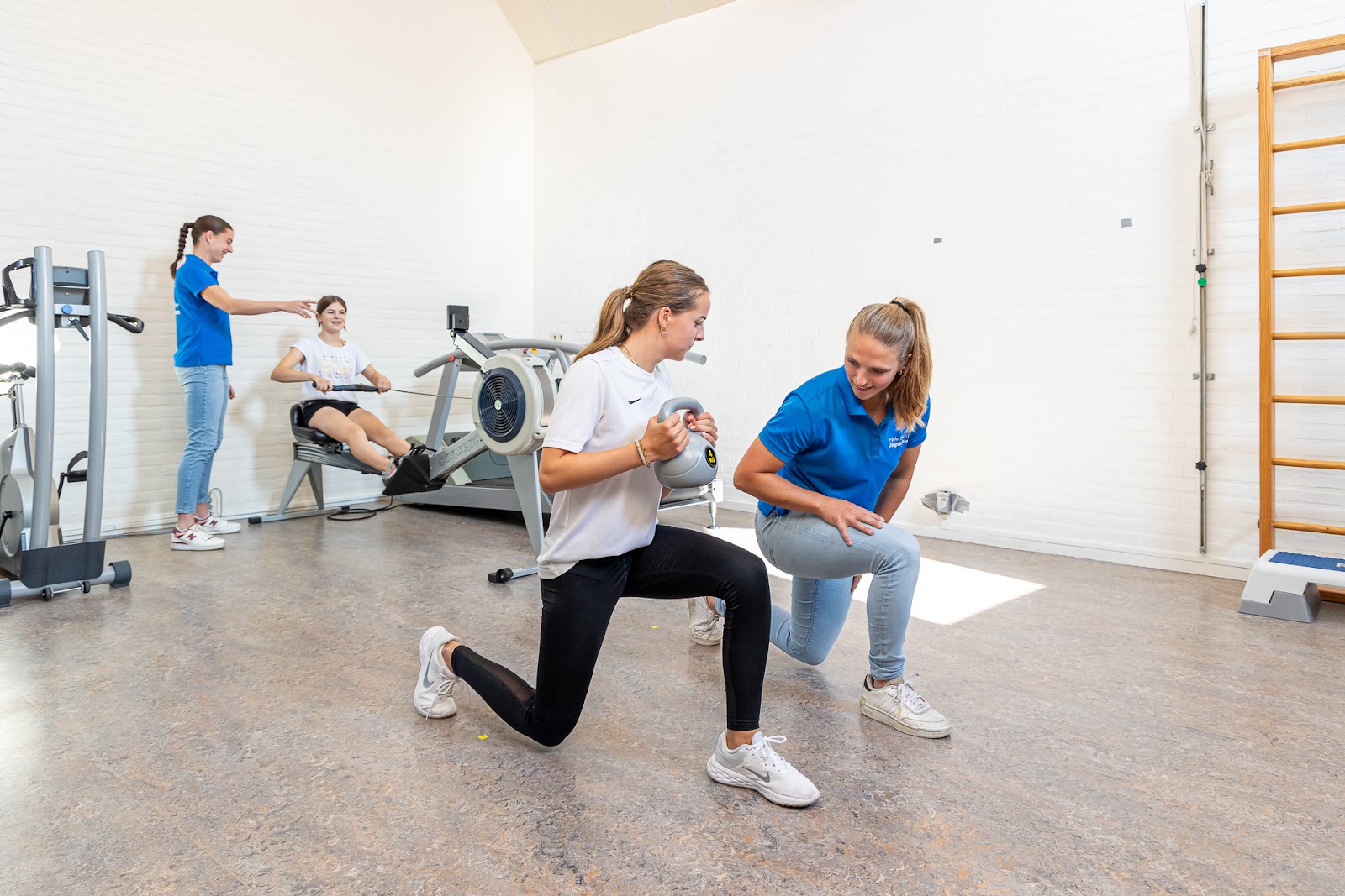 voorkom shin splints Sportieve vrouw die een kettlebell vasthoudt voorkom shin splints in een wit shirt en zwarte sportbroek werkt met behulp van de fysiotherapeut in een blauw shirt