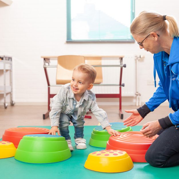 Kindje wordt geholpen met kinderfysiotherapie bij kind moeite met rennen en springen